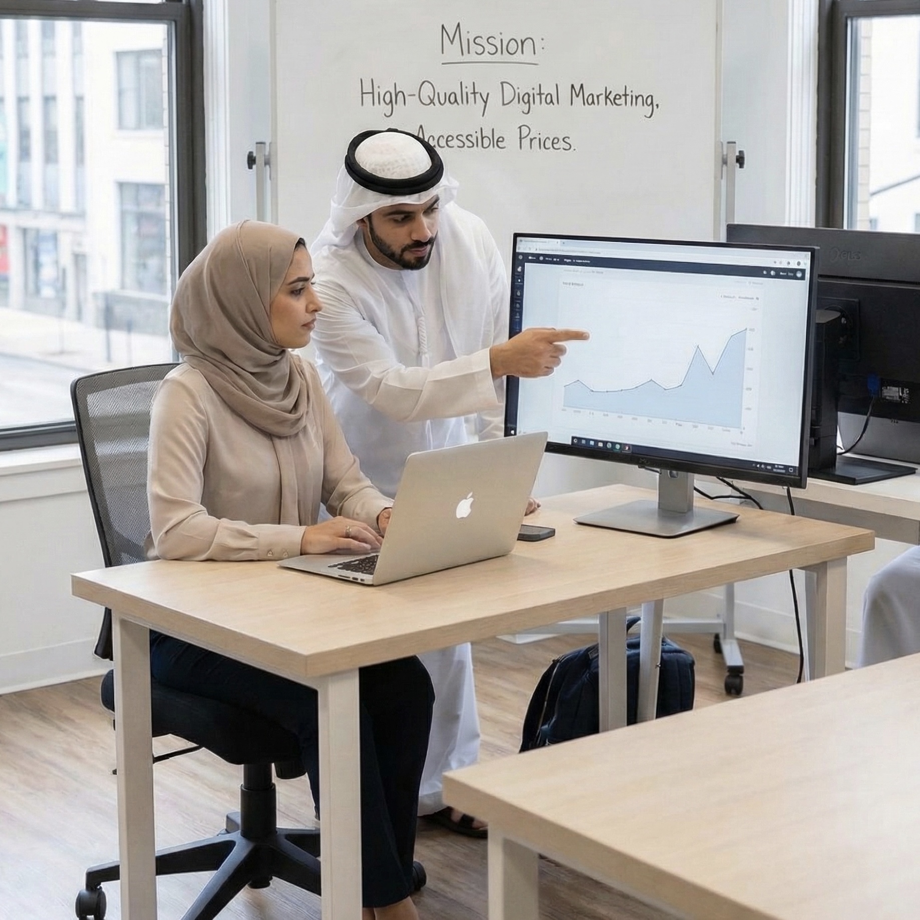 A professional Arab man and woman in a modern office analyzing an upward-trending line graph on a computer monitor. The man is pointing at the screen, and a whiteboard behind them reads 'Mission: High-Quality Digital Marketing, Accessible Prices.'